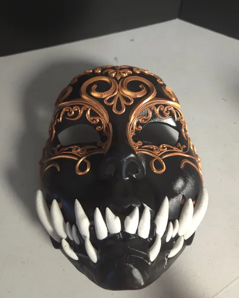 Black mask with copper filigree and white fangs